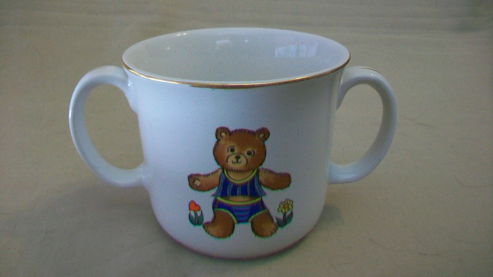 CHILDREN'S CERAMIC TWO HANDLE DRINKING CUP WITH TEDDY BEAR DESIGN