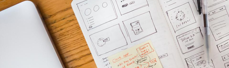 open notebook with drawings of UX design and a pen