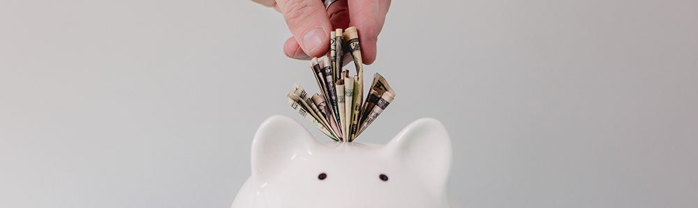 dollar bills being placed into a piggy bank