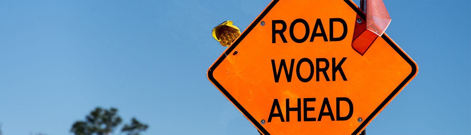 orange sign with Road Work Ahead printed on it